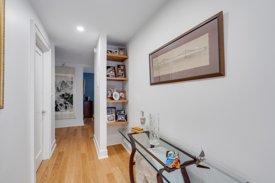 Modern hallway with new hardwood floors, crown molding, and exposed shelving.